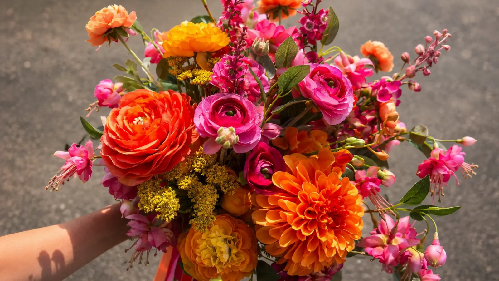 Hand holding a bright colorful garden wedding bouquet with orange dahlias, ranunculus and pink blossoms Colorful Wedding Bouquets