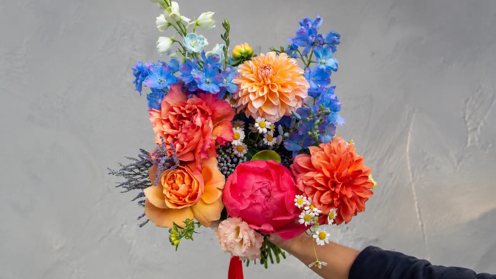 Bright orange and blue wedding bouquet with delphiniums, roses and dahlias