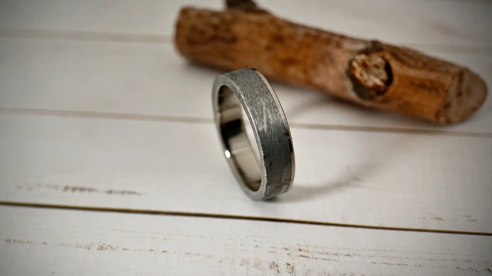 A brushed meteorite wedding ring is displayed upright on a surface, showcasing its authentic meteorite texture and polished comfort-fit interior