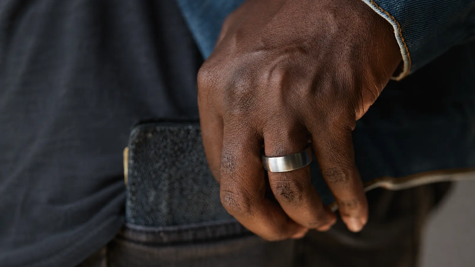 A close-up of a hand wearing a brushed titanium wedding ring, showcasing its matte finish, lightweight feel and modern minimalist appearance