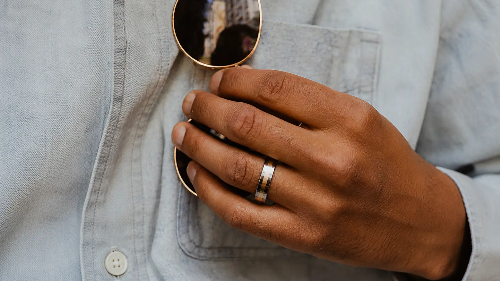 A close-up of a hand wearing a brushed tungsten wedding ring, showcasing its contemporary finish and durable design for daily use