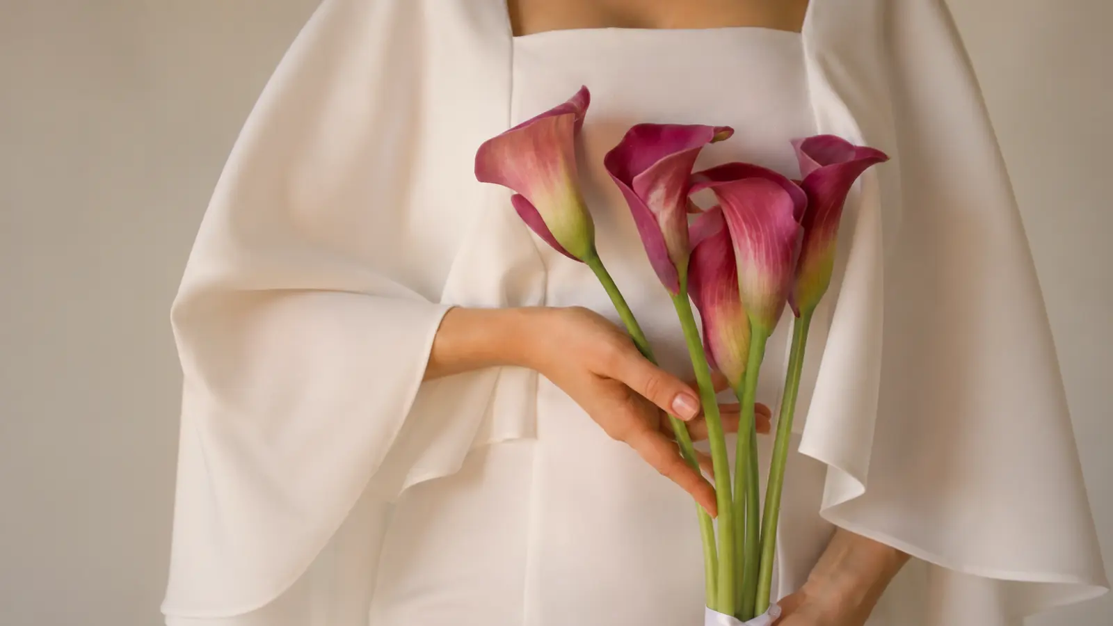 Bride holding a modern bouquet of deep burgundy calla lilies with long green stems