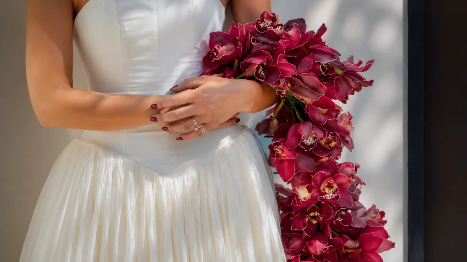 Bride holding a cascading bridal bouquet styles made with burgundy orchids
