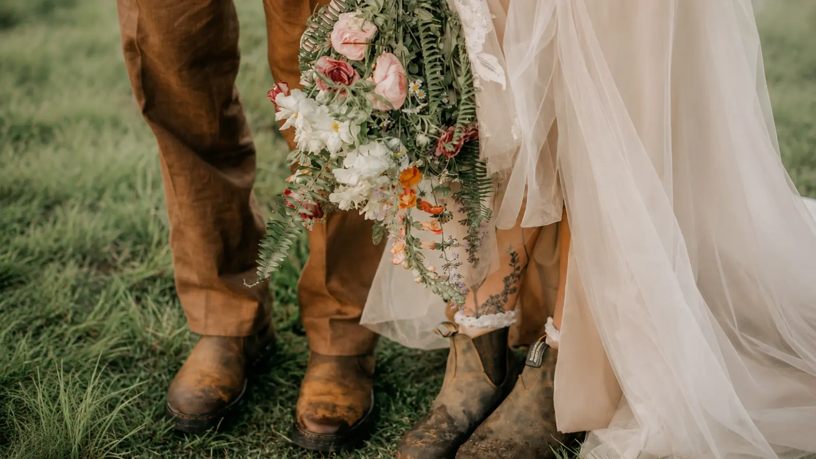 Bride holding a cascading rustic wedding bouquet with ferns and garden flowers
