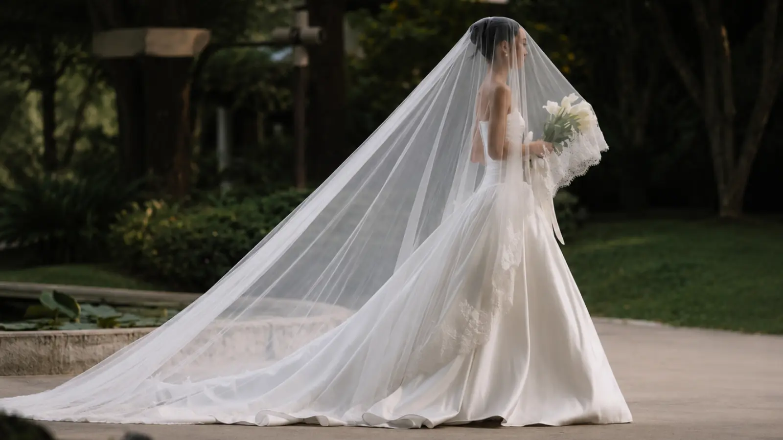 Side profile of a bride wearing a cathedral wedding veil with an extra long flowing train and lace details