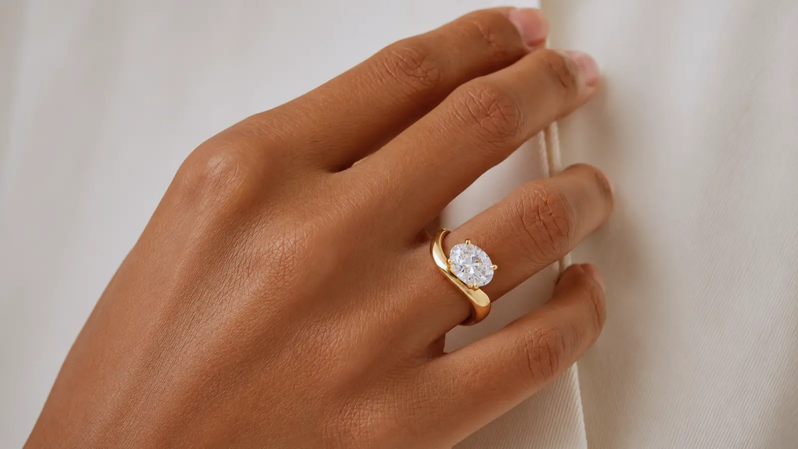 A hand holding a celestial curved wedding band with engraved stars and graduated diamonds in polished yellow gold