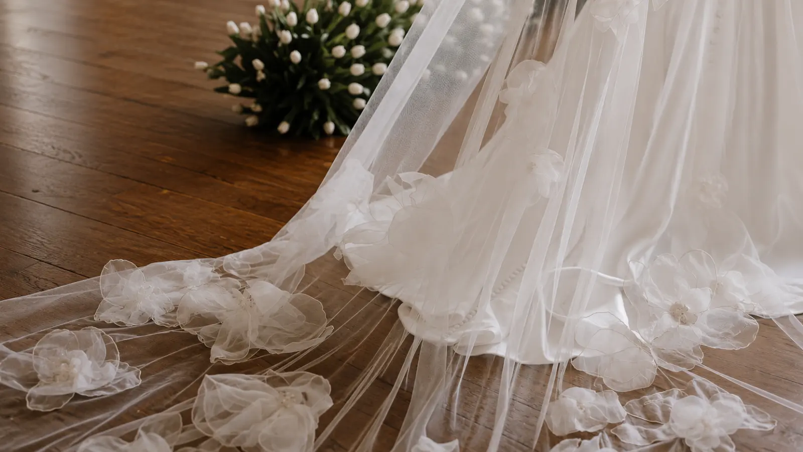 Bride wearing a chapel wedding veil with floral appliqués extending beyond the dress, illustrating a graceful medium-long wedding veil length