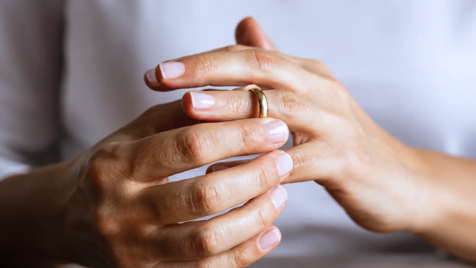 Hands adjusting a gold wedding band to check for a comfortable and secure fit on the finger