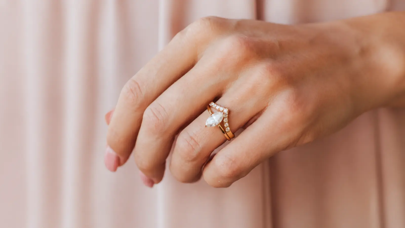 A marquise engagement ring paired with a chevron diamond wedding band on a woman's hand