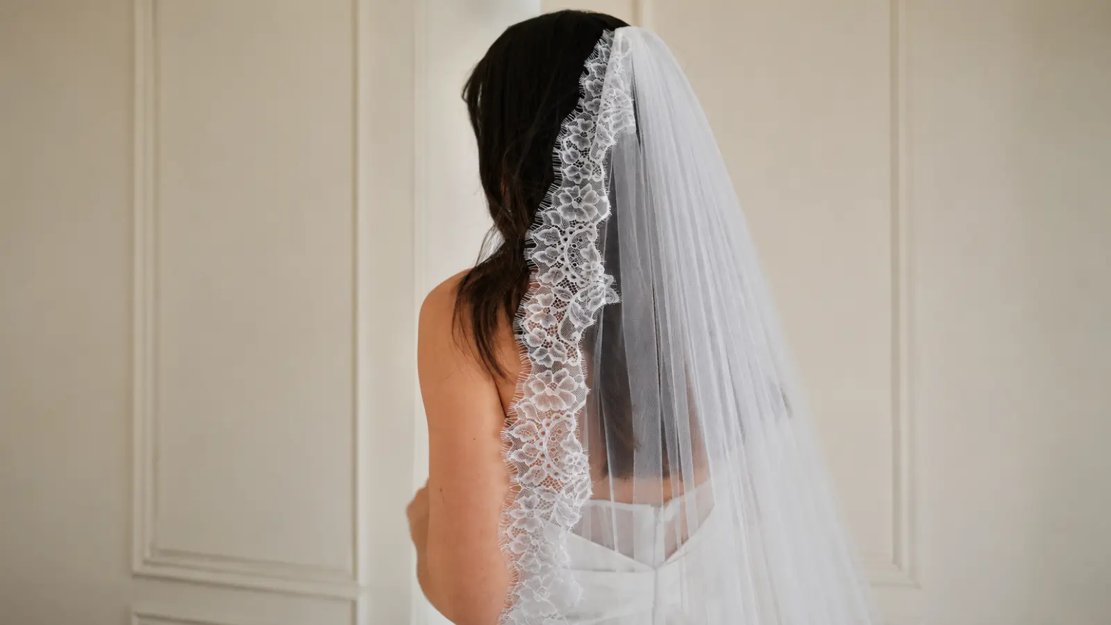 Bride wearing a classic mantilla wedding veil with floral lace trim cascading down the back