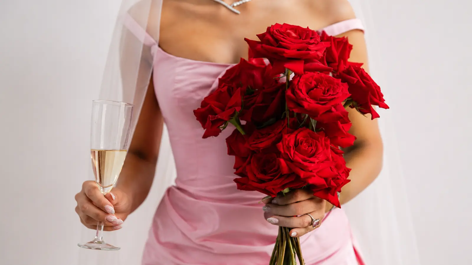 Bride in a blush pink dress holding a classic red rose wedding bouquet with rich velvety blooms