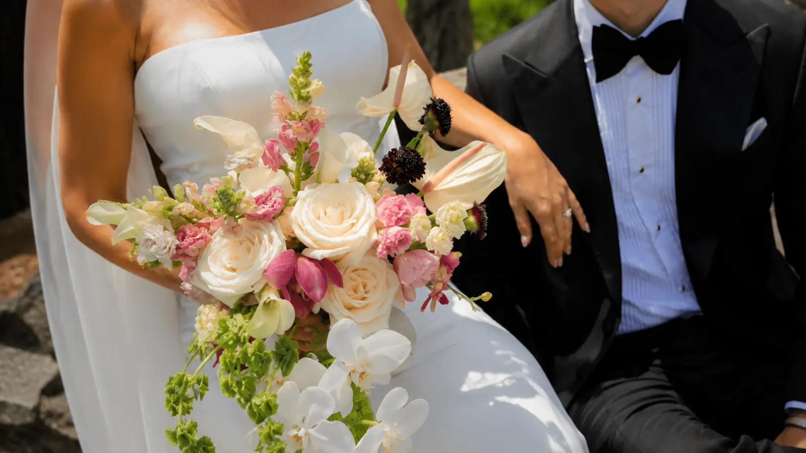 Bride holding a classic spring wedding bouquet with white roses, orchids, anthuriums and pastel seasonal flowers