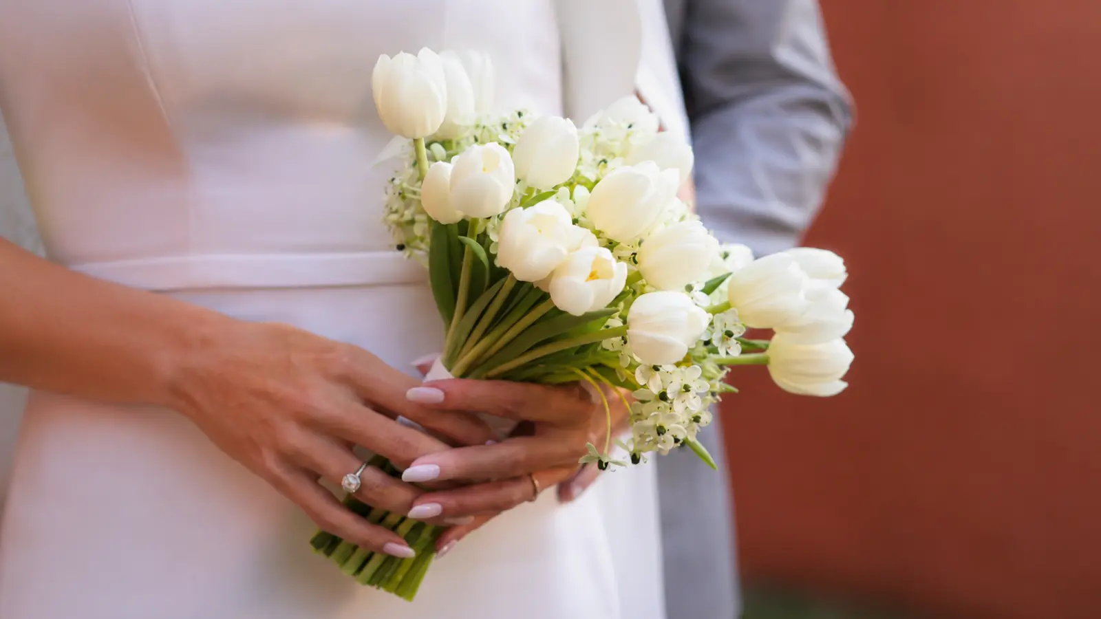 Bride holding a classic white tulip wedding bouquet accented with small white seasonal flowers