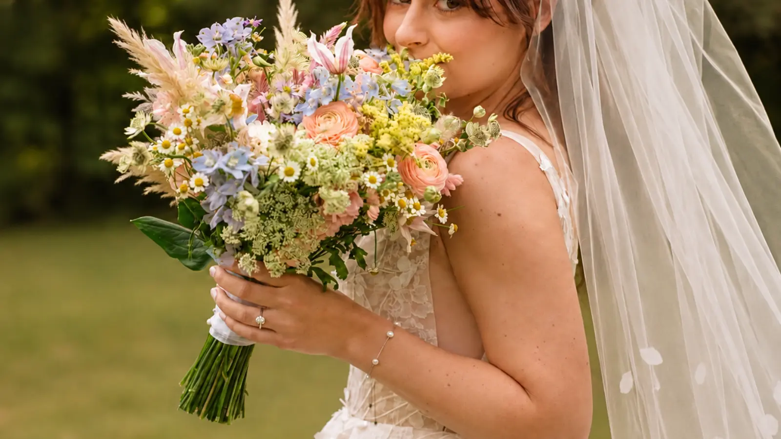 Bride holding a colorful boho wedding bouquet with wildflowers and pampas grass