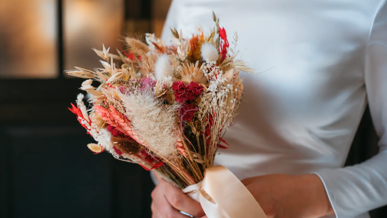 Bride holding a colorful dried boho wedding bouquet with preserved flowers