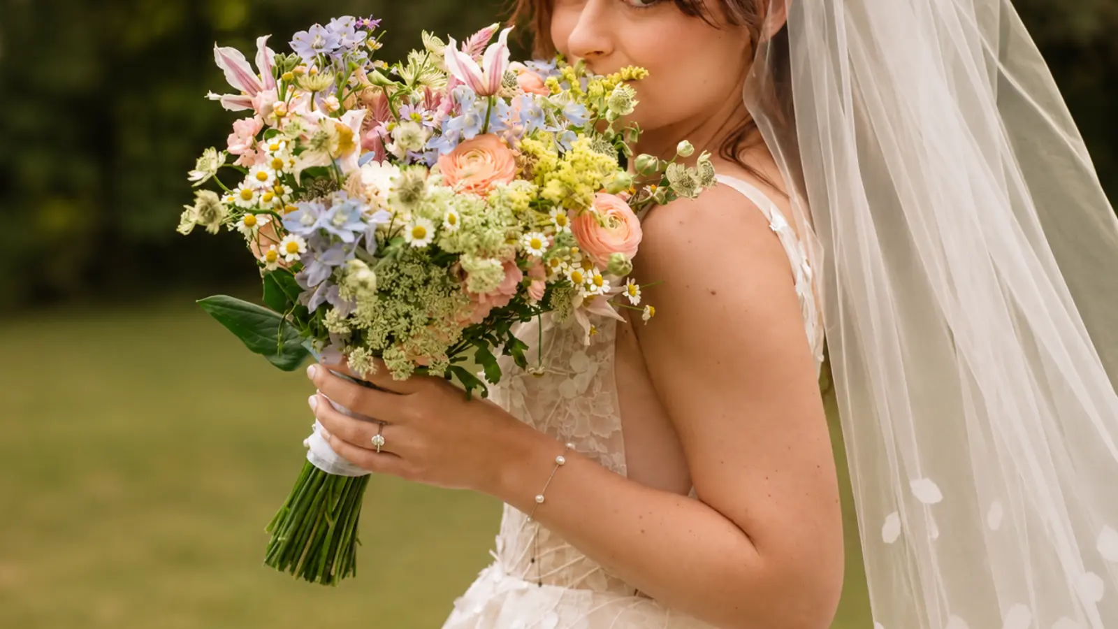Bride holding a colorful fresh seasonal wedding bouquet with garden flowers