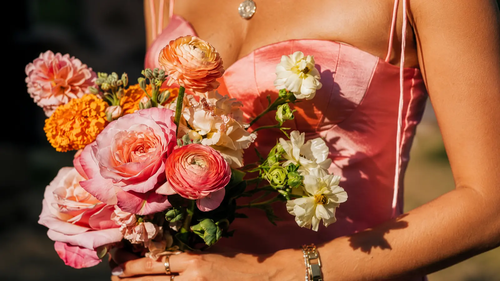 Bridesmaid holding a colorful pink and orange garden-style wedding bouquet