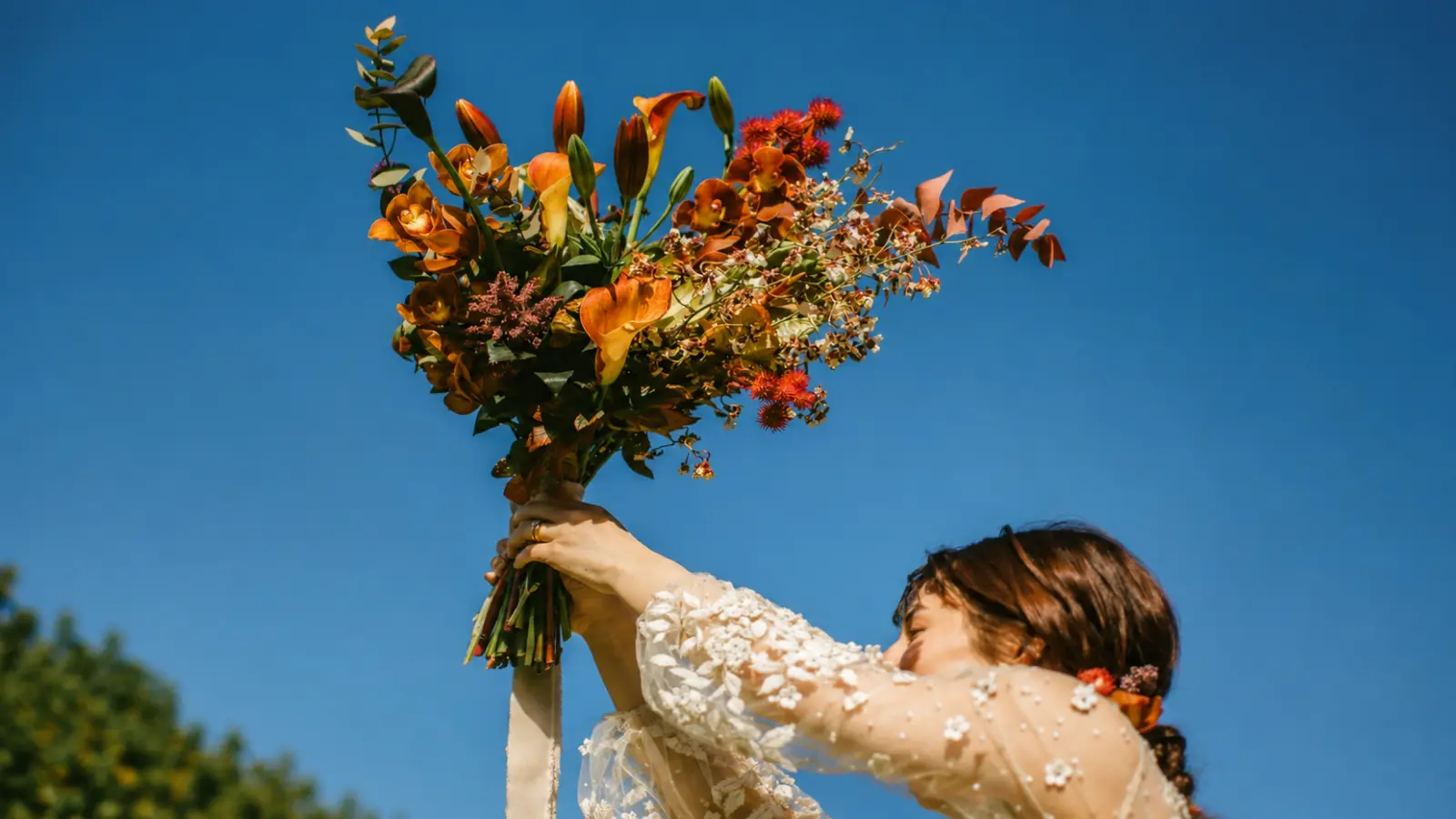 Bride raising a colorful wedding bouquet during a modern bouquet toss celebration