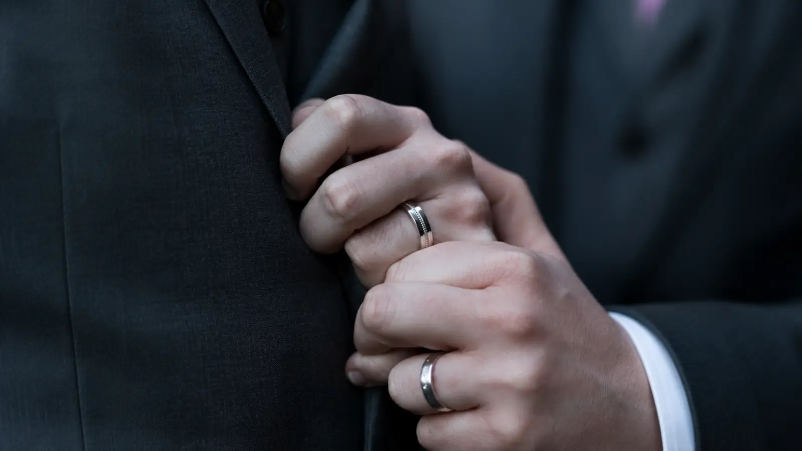 Bride and groom wearing complementary wedding rings that are not identical