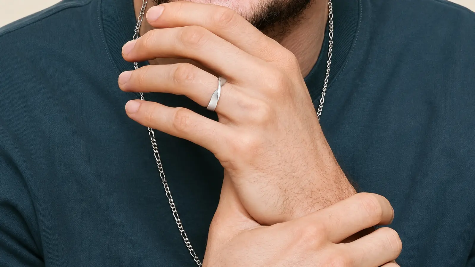 A man wearing a contemporary wedding ring with sculptural lines and a modern satin finish on his left hand