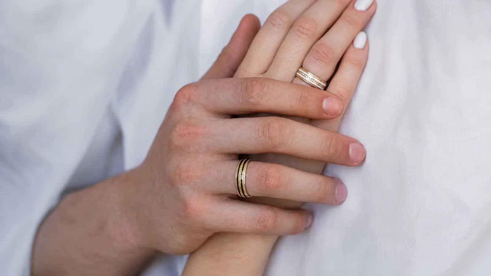 Couple wearing coordinating gold wedding rings with matching design details