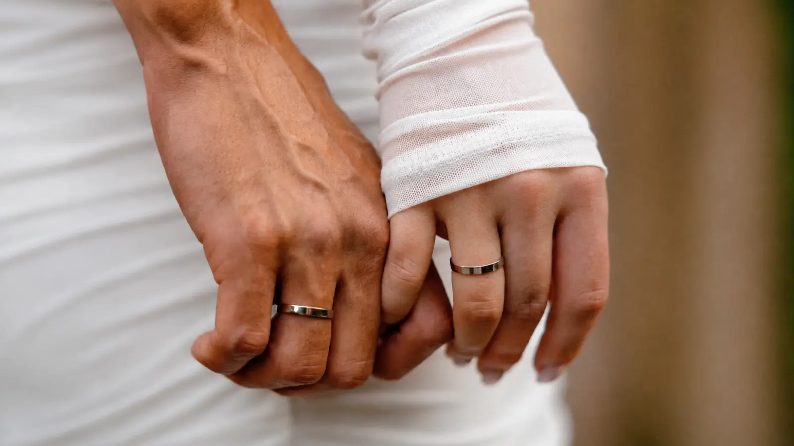 Bride and groom holding hands while wearing matching polished wedding rings