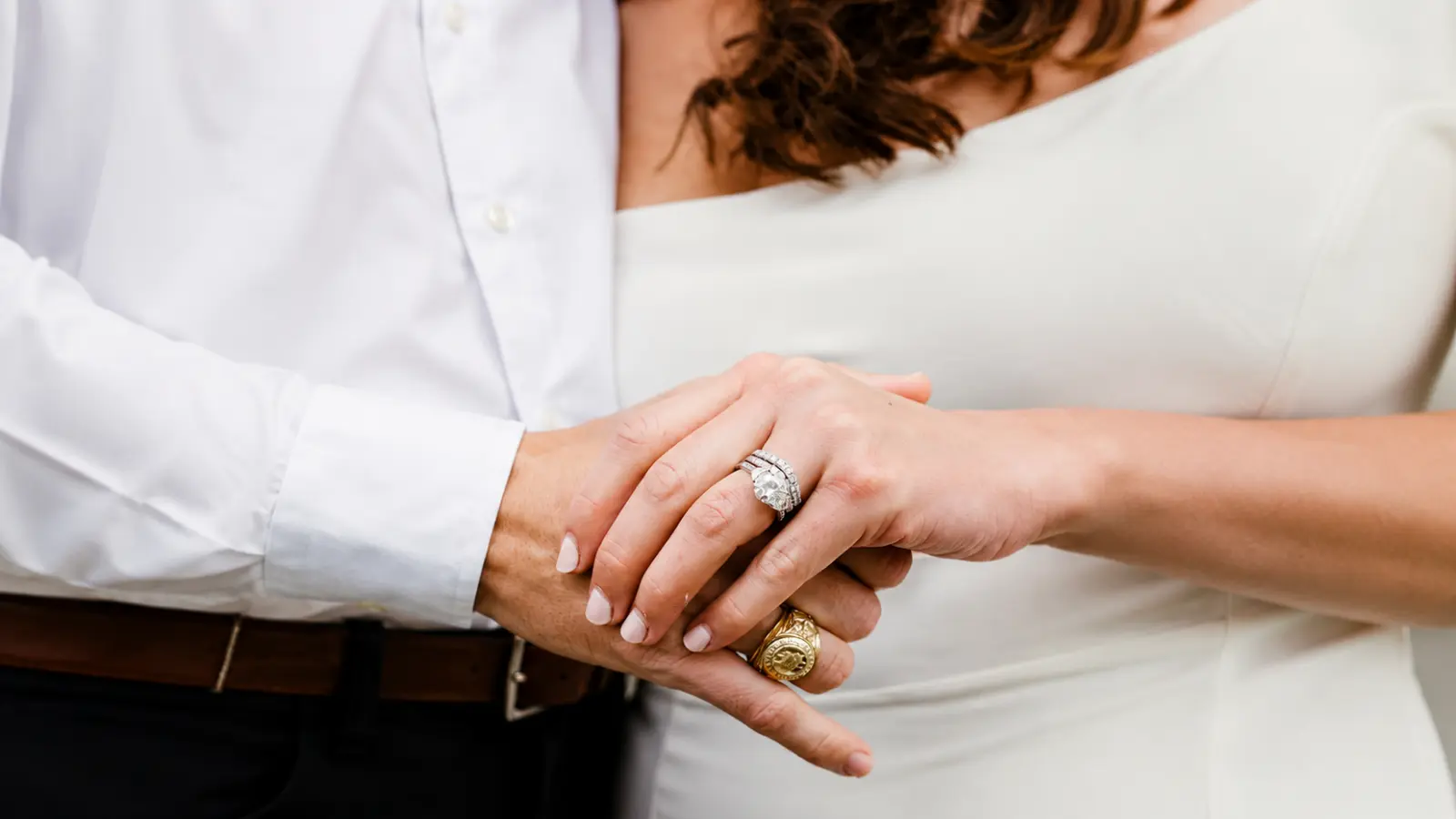A couple embracing while wearing a diamond anniversary ring, engagement ring, and wedding band, highlighting the tradition of celebrating important marriage milestones with meaningful jewelry