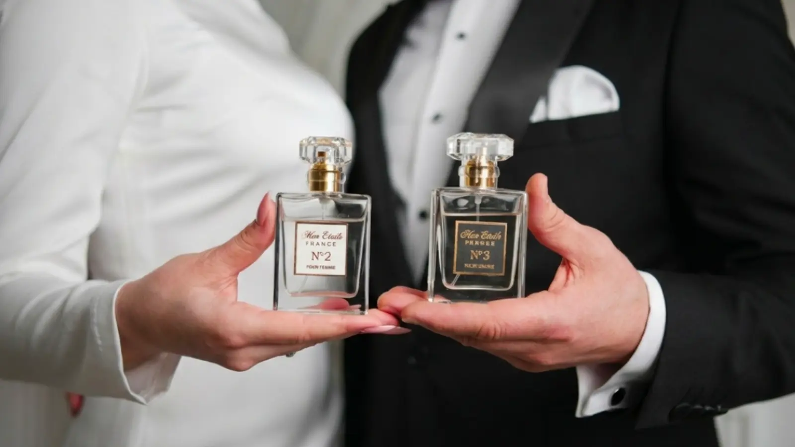 A bride and groom holding matching wedding perfume bottles together, showcasing complementary fragrances chosen to create a shared scent memory and a coordinated wedding day experience