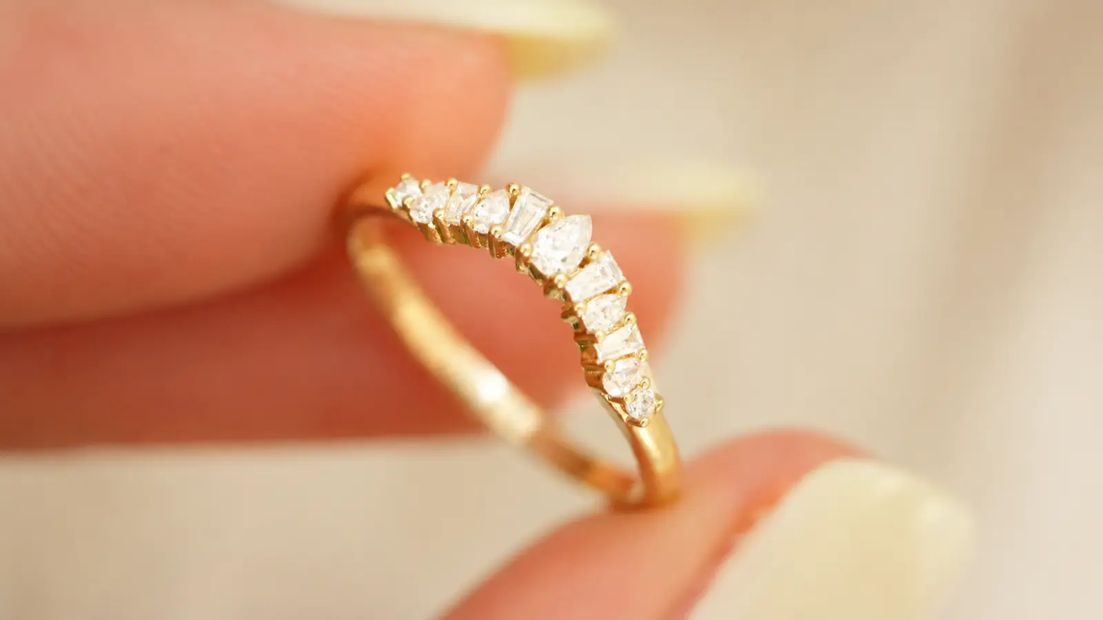 A close-up of a curved diamond wedding ring enhancer featuring graduated diamonds in a polished yellow gold setting