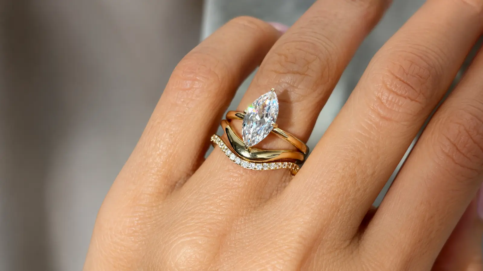 A marquise engagement ring paired with a curved gold wedding band and diamond accent band Wedding Bands for Marquise Engagement Rings