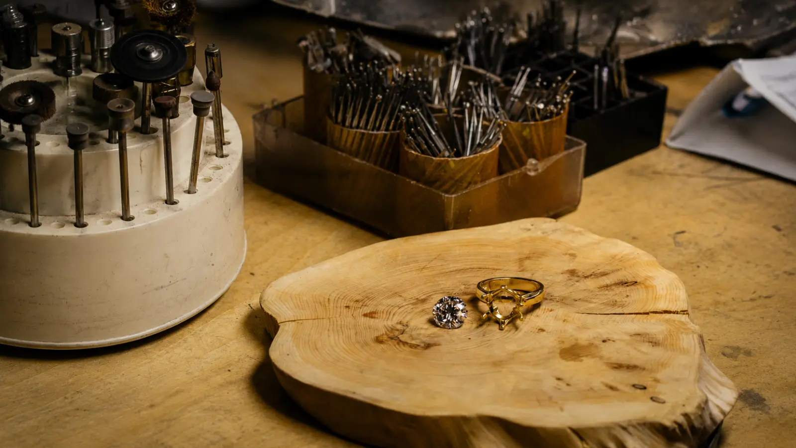A jeweler's workbench displaying tools, gemstones and ring settings prepared for creating a custom wedding ring