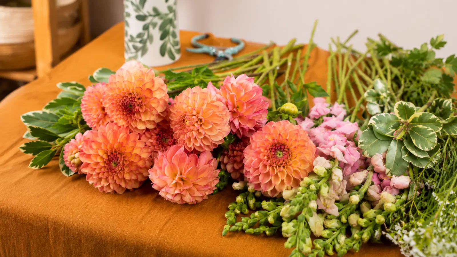 Fresh orange dahlias displayed alongside greenery and companion flowers for wedding bouquet design