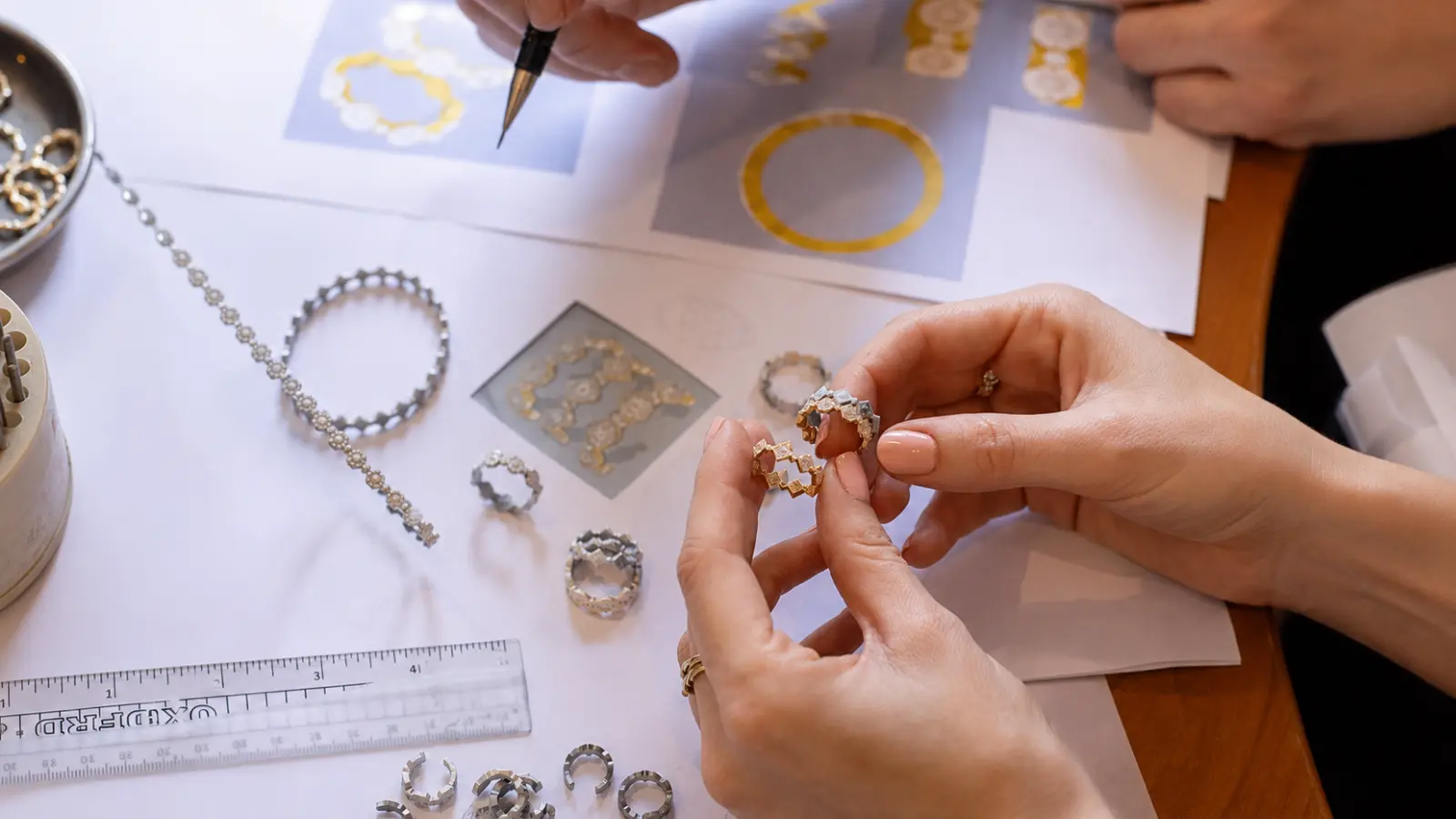 Two people reviewing sketches and ring samples with a jeweler during the custom wedding ring design process