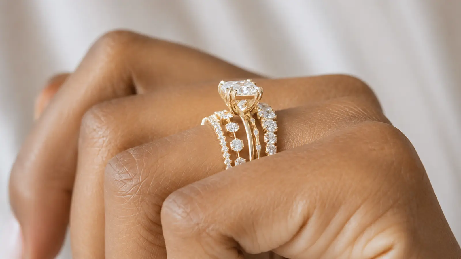 Detailed close-up of stackable wedding rings with several diamond bands surrounding a solitaire engagement ring, emphasizing the layered design and fine jewelry craftsmanship