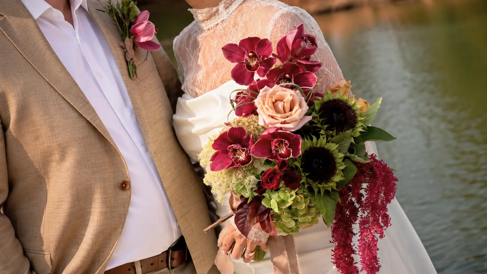 Bride holding a dramatic burgundy wedding bouquet beside the groom wearing a matching orchid boutonniere