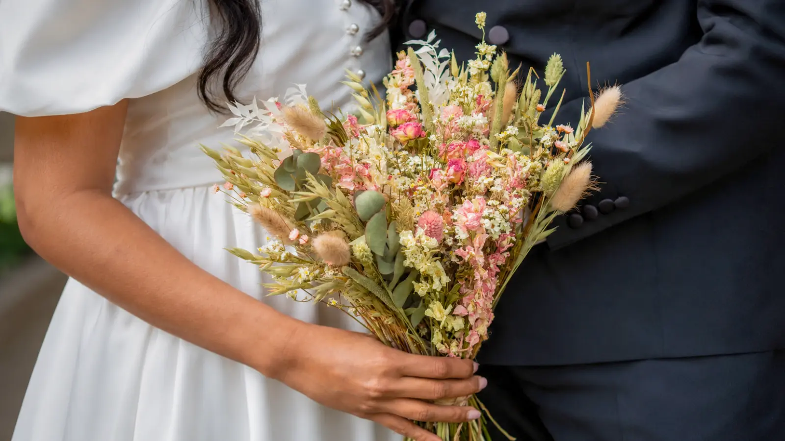 Bride holding a natural dried boho wedding bouquets with grasses and preserved flowers