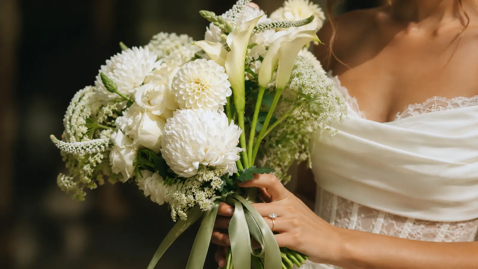 Bride holding an elegant simple white wedding bouquet with fresh flowers