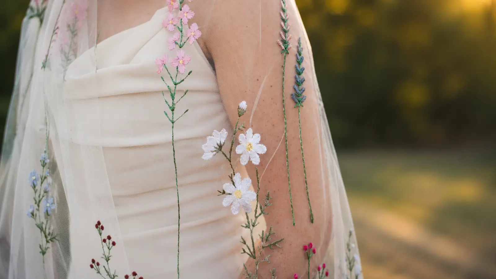 Bride wearing a floral wedding veils embroidered with colorful wildflowers over a minimalist wedding dress