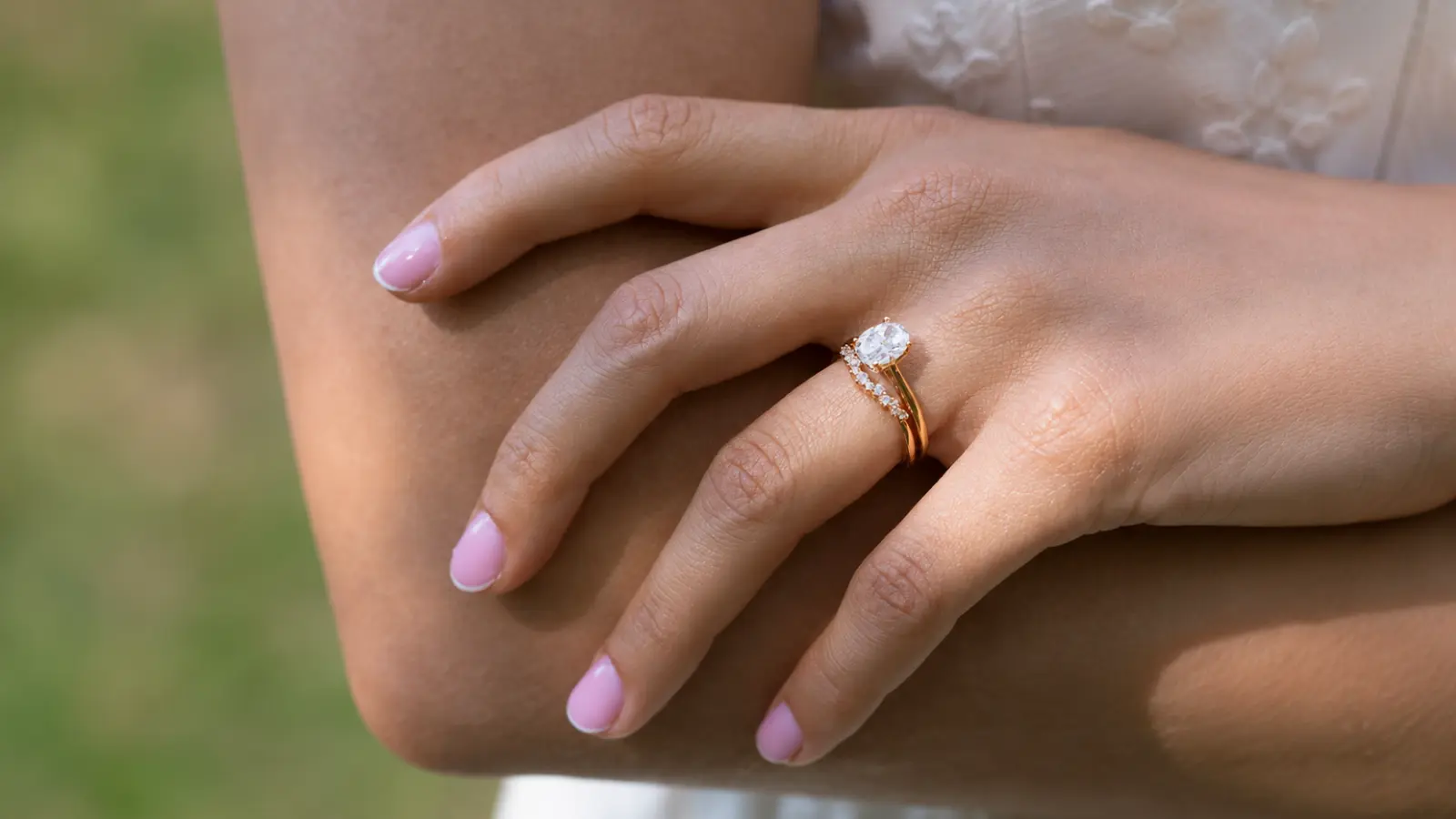 Oval engagement ring paired with a curved diamond wedding band on a bride's hand