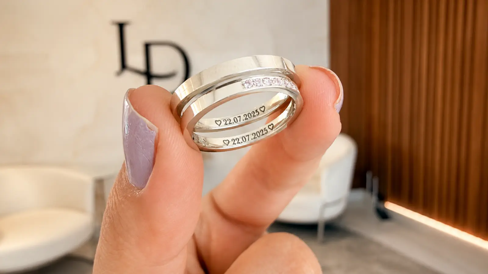 Matching engraved wedding rings with a wedding date held between fingers