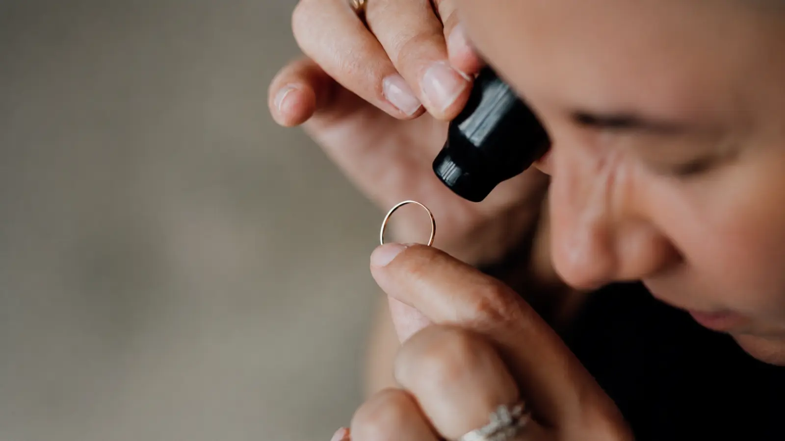 Close-up of a jeweler examining a wedding ring with a loupe during an insurance appraisal process