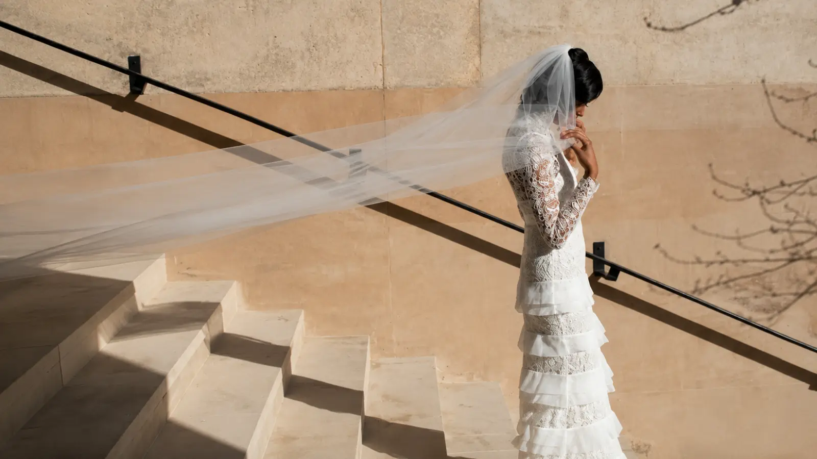 Bride wearing an extra long cathedral wedding veil with a sweeping train while holding a white bouquet