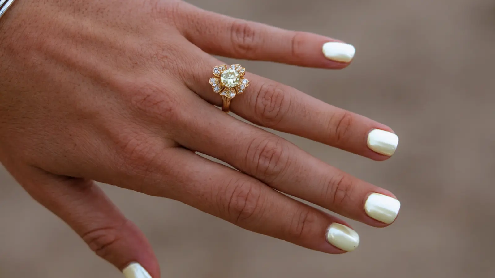 A hand wearing a floral halo engagement ring with a flower-shaped diamond setting in yellow gold Floral Wedding Rings