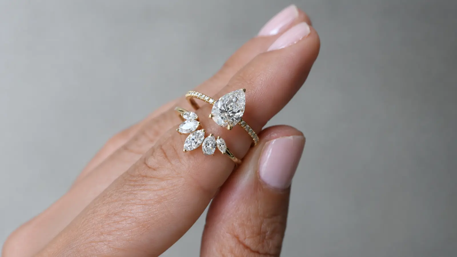 A pear shaped engagement ring paired with a floral-inspired wedding band featuring marquise diamonds