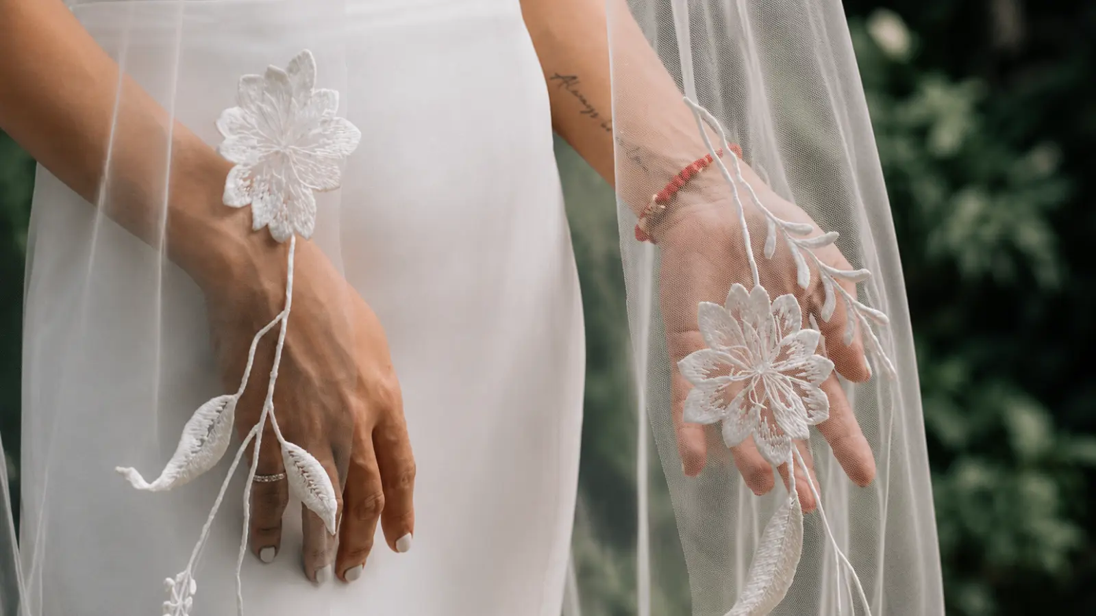Close-up of a floral wedding veil with embroidered floral appliqués draping beside a minimalist bridal dress