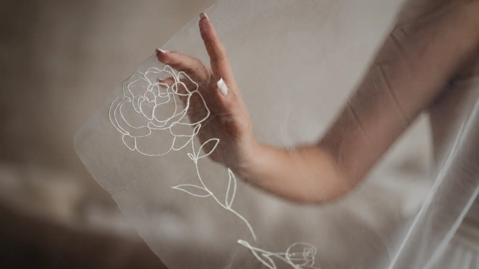 Close-up of a floral wedding veil with delicate botanical flower embroidery on sheer illusion tulle