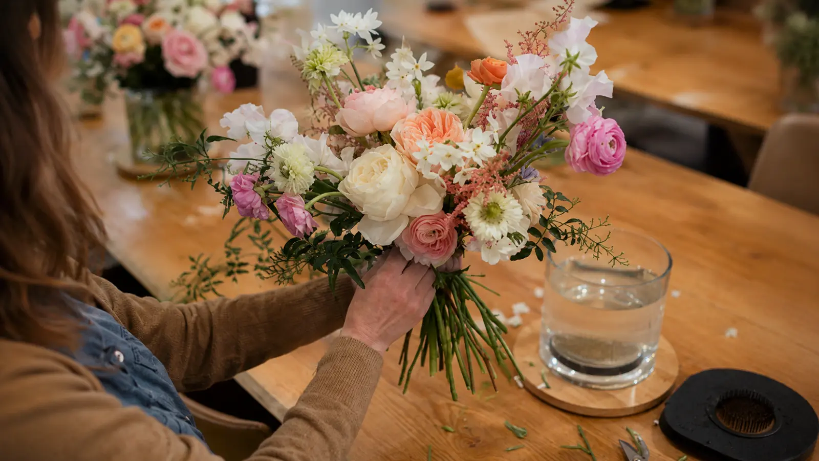 Florist holding a fresh garden wedding bouquet with roses, ranunculus and sweet peas