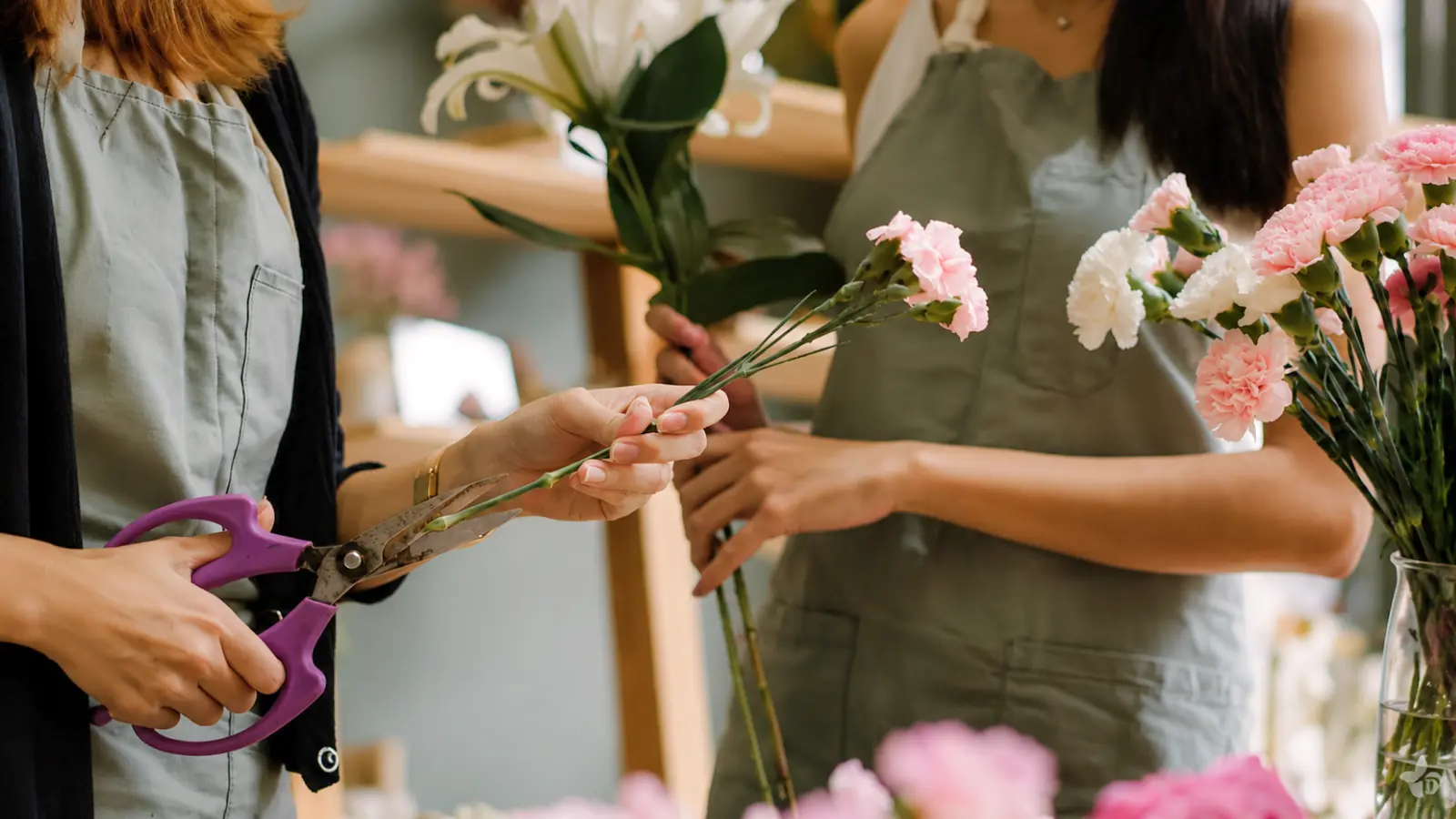 Florists preparing a fresh wedding bouquet with seasonal flowers and floral tools