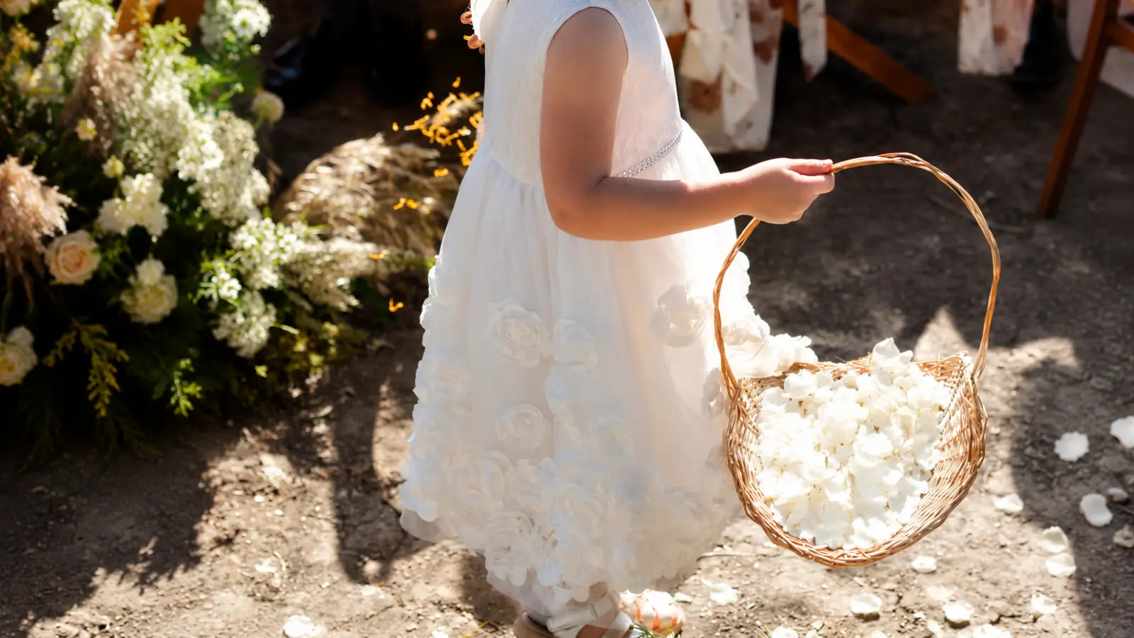 Flower girl carrying a basket filled with white rose petals for the ceremony Flower Girl Bouquets