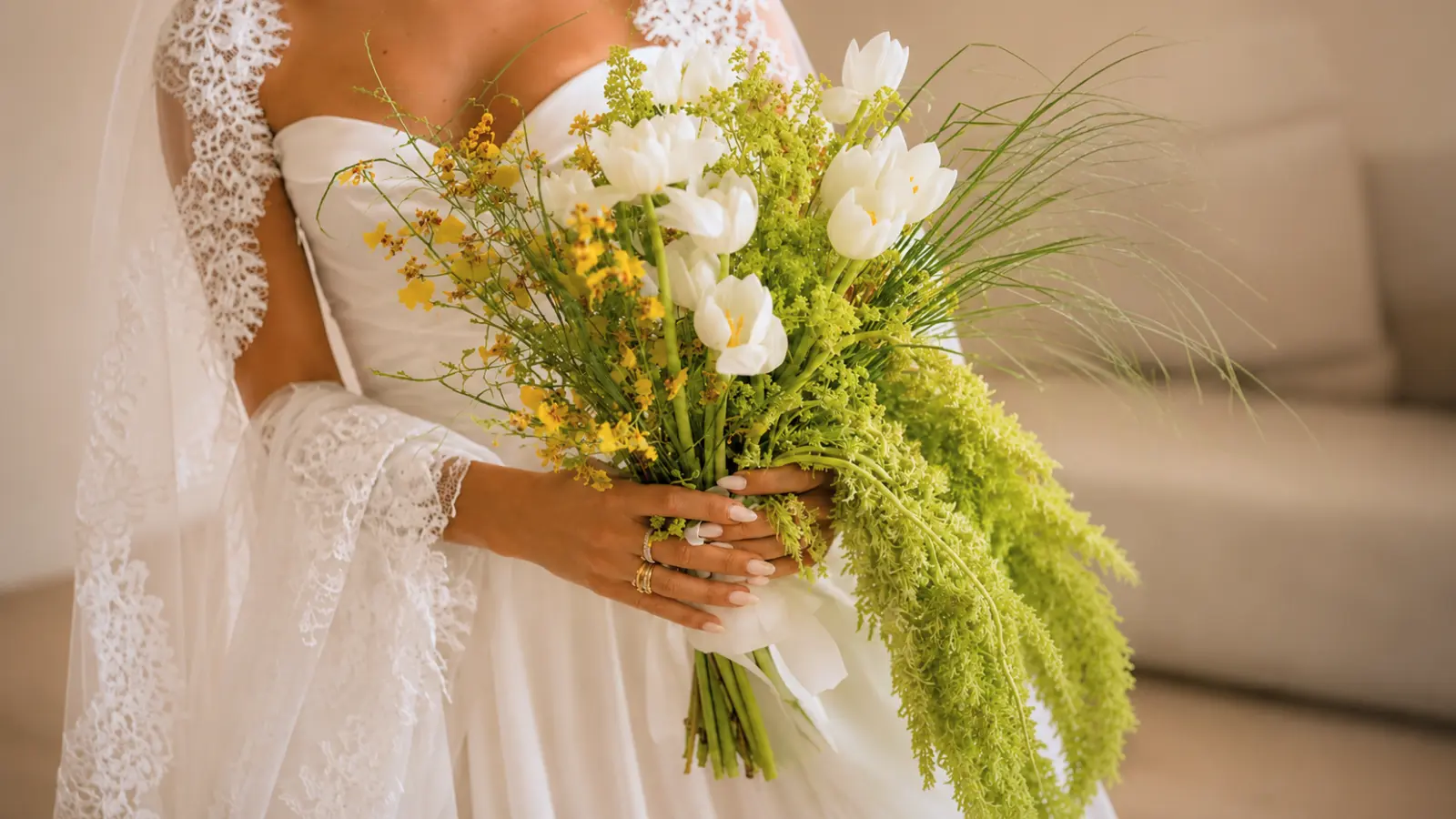 Bride holding a fresh spring wedding bouquet with white tulips, greenery and seasonal flowers